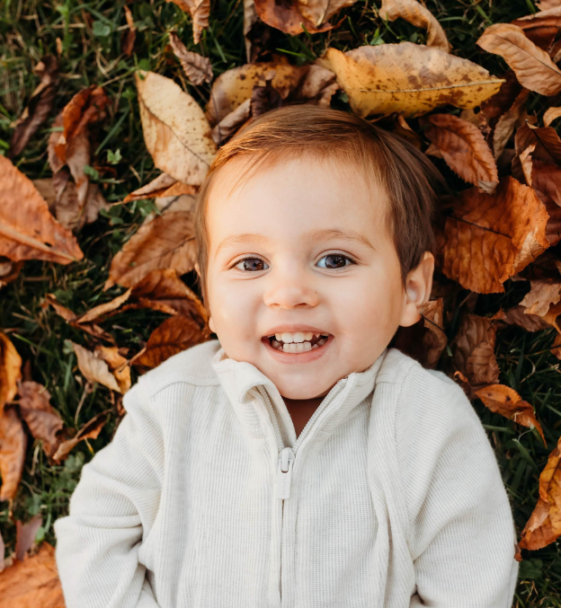 Little boy laying in a pile of leaves