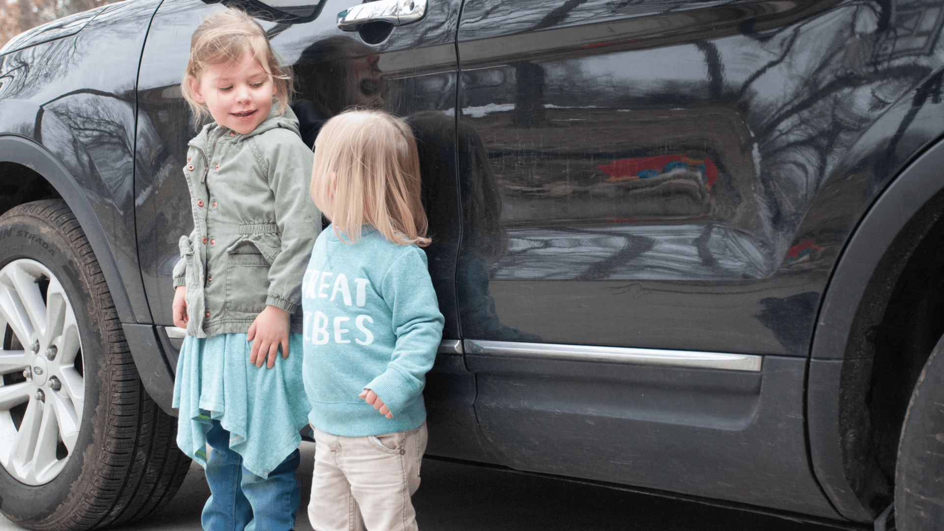 two kids on side of car