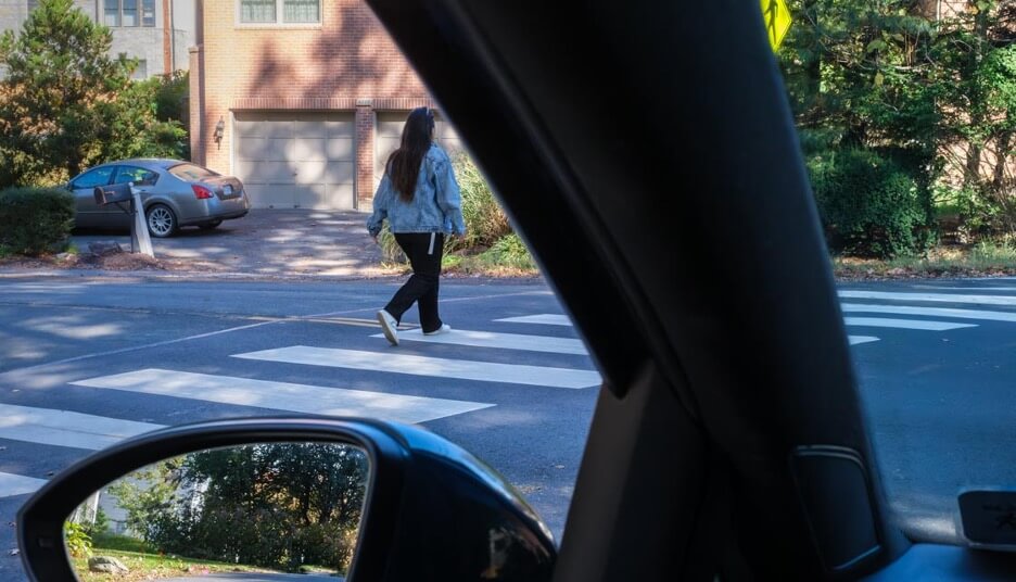 view from driver's perspective of a woman crossing the street