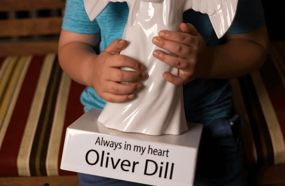Owen Dill, 7, holds a memorial angel in honor of his younger brother Oliver that sits outside his home in Evansville, Ind., Wednesday, June 16, 2021. His brother Oliver, also known as "Ollie," died in 2019 after accidentally being forgotten in a car on the University of Southern Indiana campus.