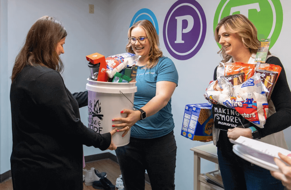 Be Kind for Ollie founder Jamie Dill, left, receives donations from Center for Pediatric Therapy's Maria Banks, center, and Alyssa Anderson, right, for her non-profit's annual benefit dinner in Evansville, Ind. 